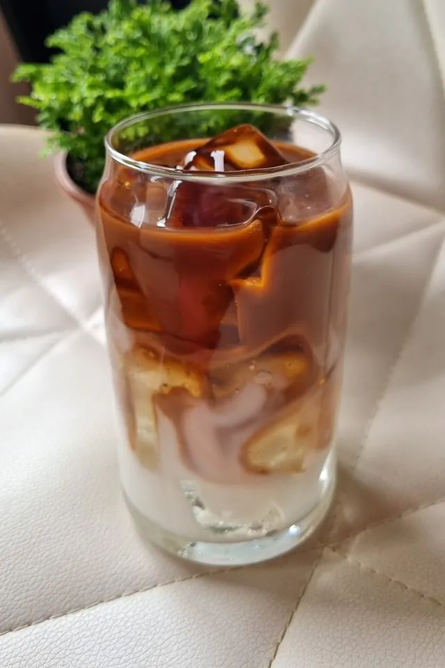 Iced latte cremoso em copo de vidro, a bebida que inspirou a vela