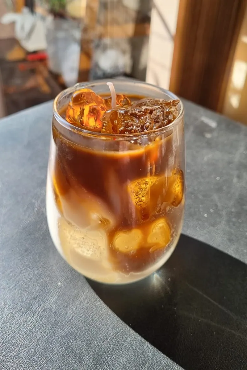 Vela Iced Latte artesanal em copo arredondado, com camadas de leite e café e gelos de cera
