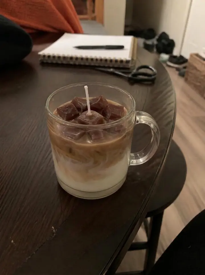 Vela artesanal marrom em uma caneca sobre uma mesa de casa