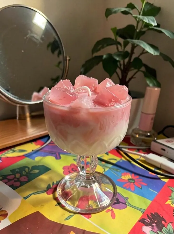Vela artesanal rosa em uma taça sobre uma penteadeira colorida
